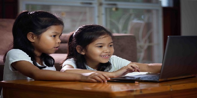 Two asian child girls using notebook to learning online technology with her sister together. Concept of online education, social distance learning at home during quarantine and school holidays.